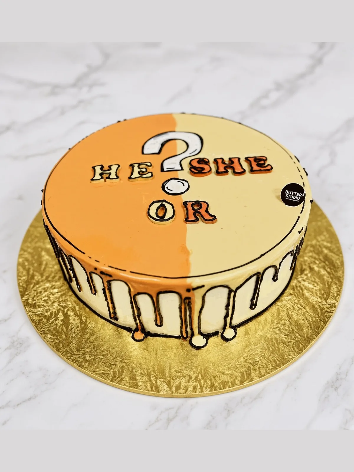 Orange and yellow comic-style gender reveal cake with He or She lettering