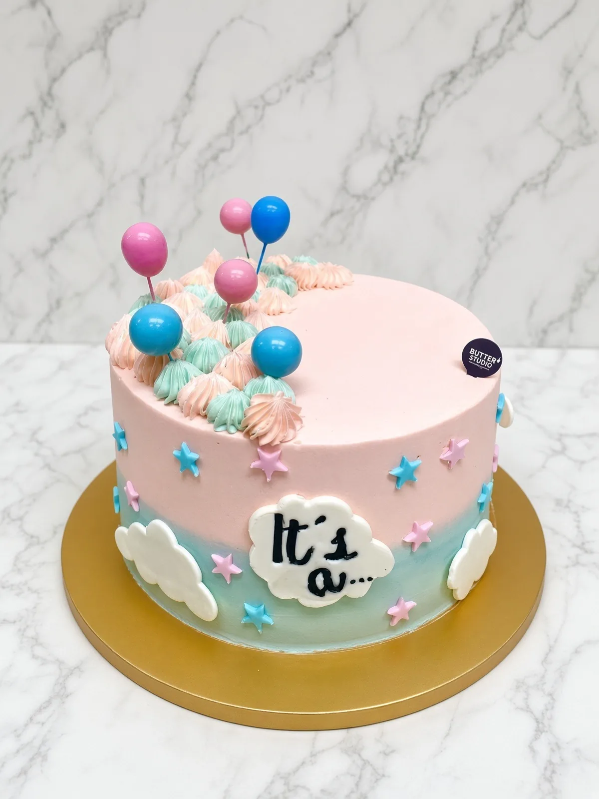 Pastel pink and blue gender reveal cake with balloon and star decorations