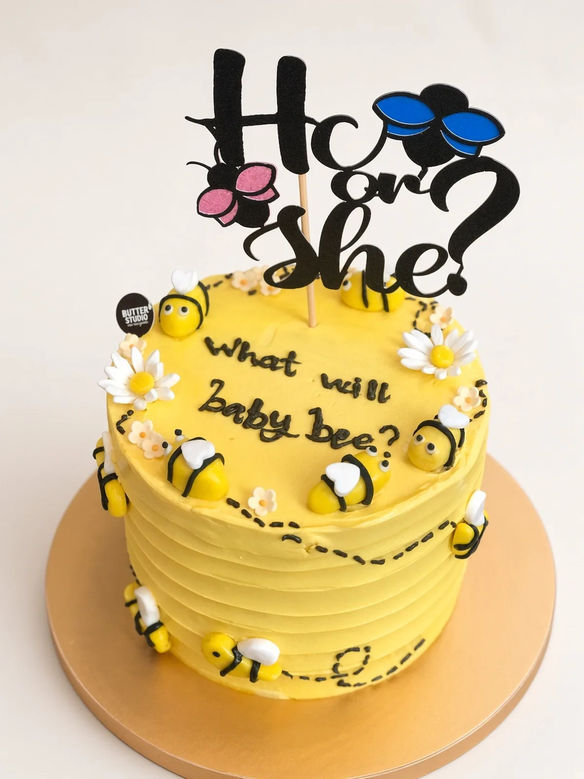 Yellow bee-themed gender reveal cake with a He or She topper